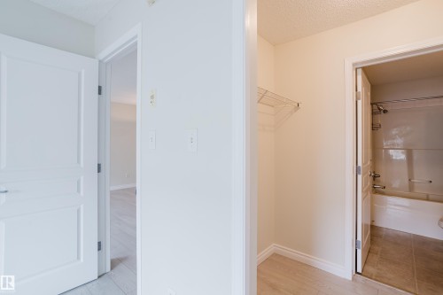 The property features light-colored flooring throughout, with a bathroom visible including a shower and bathtub combination, and a wire rack shelf - 113 309 Clareview Station Drive, Edmonton, AB - Indoor