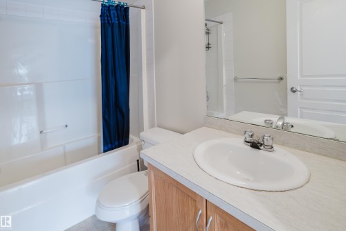 Bathroom featuring a bathtub with a shower, a vanity with a counter and sink, and a mirror - 113 309 Clareview Station Drive, Edmonton, AB - Indoor Photo Showing Bathroom