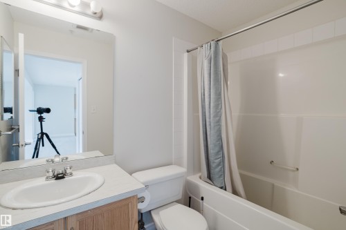 The bathroom features a vanity with an integrated sink, a toilet, and a combination shower and tub - 113 309 Clareview Station Drive, Edmonton, AB - Indoor Photo Showing Bathroom
