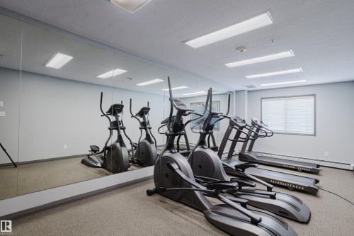 The property features a fitness area with cardio equipment, including elliptical machines and treadmills - 113 309 Clareview Station Drive, Edmonton, AB - Indoor Photo Showing Gym Room