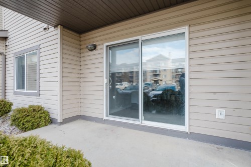 The property features a concrete patio with an overhead cover, sliding glass doors, and light-colored siding - 113 309 Clareview Station Drive, Edmonton, AB - Outdoor With Exterior