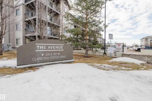 The property features a stone sign with directional information for "The Avenue" and "Clareview Station Drive." The building features exterior balconies with dark railings - 113 309 Clareview Station Drive, Edmonton, AB - Outdoor
