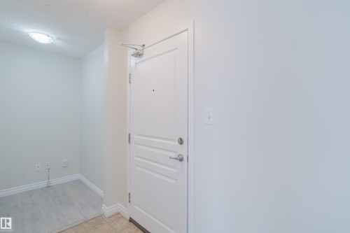 Entryway featuring a light-colored door with silver hardware, a ceiling light fixture, and light-toned flooring - 113 309 Clareview Station Drive, Edmonton, AB - Indoor Photo Showing Other Room