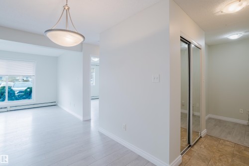 Bright interior space featuring light-colored flooring, white walls, a large window with blinds, and a mirrored closet - 113 309 Clareview Station Drive, Edmonton, AB - Indoor Photo Showing Other Room