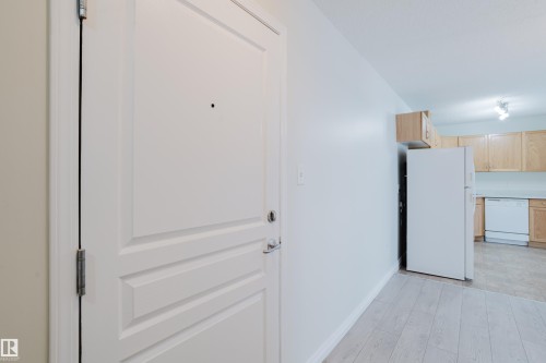 The property features light-colored flooring, a white paneled door, and a kitchen with light wood cabinetry and white appliances - 113 309 Clareview Station Drive, Edmonton, AB - Indoor