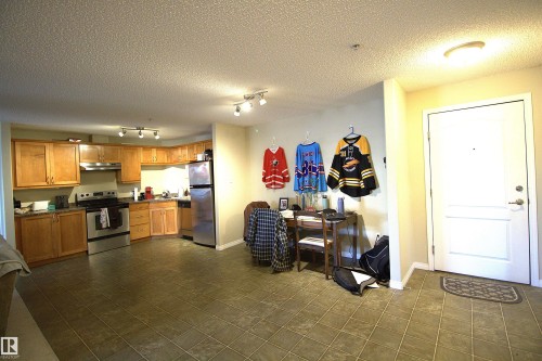 The kitchen features wood cabinetry, stainless steel appliances, and track lighting - 1204 330 Clareview Station Drive, Edmonton, AB - Indoor Photo Showing Kitchen