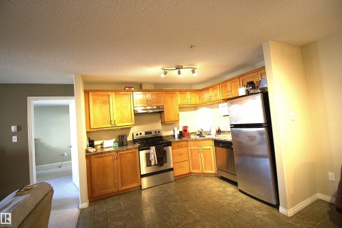 Kitchen featuring wood cabinetry, stainless steel appliances, and dark tile flooring - 1204 330 Clareview Station Drive, Edmonton, AB - Indoor Photo Showing Kitchen
