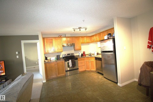 The kitchen features a full complement of stainless steel appliances, wood cabinetry, and track lighting - 1204 330 Clareview Station Drive, Edmonton, AB - Indoor Photo Showing Kitchen