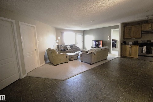 Open concept living area with tiled flooring, leading to a carpeted section - 1204 330 Clareview Station Drive, Edmonton, AB - Indoor Photo Showing Living Room