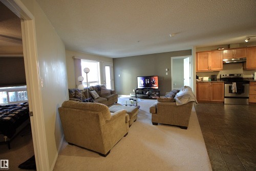 The inviting living area features a carpeted floor, large windows providing natural light, and a door leading to an outdoor space - 1204 330 Clareview Station Drive, Edmonton, AB - Indoor Photo Showing Living Room