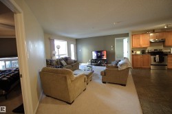 The inviting living area features a carpeted floor, large windows providing natural light, and a door leading to an outdoor space - 