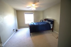 This room features light-colored carpeting, a window with a blind, and a ceiling fan - 