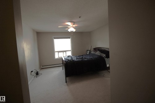This room features light-colored carpeting, a window with blinds, and a ceiling fan with integrated lighting - 1204 330 Clareview Station Drive, Edmonton, AB - Indoor Photo Showing Bedroom