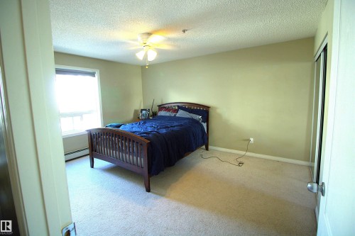 Bedroom featuring a window, light-colored carpeting, a ceiling fan, and sliding closet doors - 1204 330 Clareview Station Drive, Edmonton, AB - Indoor Photo Showing Bedroom