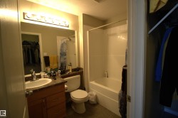 The bathroom features a vanity with a sink, a toilet, a full-size mirror with overhead lighting, and a shower-bathtub combination - 