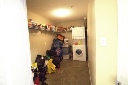This utility area features a tiled floor, a stacked washer and dryer, and wire shelving for storage - 