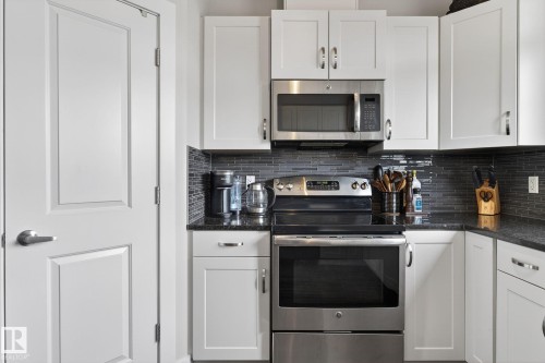 Well-appointed kitchen featuring white cabinetry, stainless steel appliances, dark granite countertops, and a subway tile backsplash - 9084 Rosenthal Link, Edmonton, AB - Indoor Photo Showing Kitchen With Upgraded Kitchen