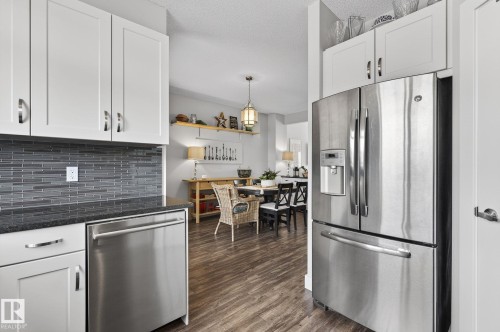 Kitchen featuring white cabinetry, a grey tile backsplash, stainless steel appliances, and dark countertops - 9084 Rosenthal Link, Edmonton, AB - Indoor Photo Showing Kitchen