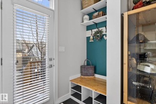 Entryway featuring a built-in wooden bench with storage cubbies, wall-mounted shelving, and a glass-paneled door with blinds providing views of exterior stairs - 9084 Rosenthal Link, Edmonton, AB - Indoor