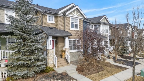 The property features a welcoming front entrance with stone accents, a covered porch, and a red front door - 9084 Rosenthal Link, Edmonton, AB - Outdoor With Facade