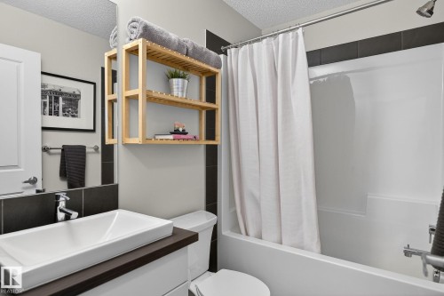 Bathroom featuring a white rectangular vessel sink, a dark wood-look vanity top, and dark tiled accents on the wall - 9084 Rosenthal Link, Edmonton, AB - Indoor Photo Showing Bathroom
