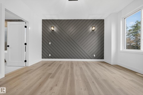 This room features light-toned flooring, a window offering views of trees and sky, and a striking accent wall with a geometric pattern - 6117 Crawford Drive, Edmonton, AB 