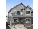 Modern two-story property featuring a gray exterior with stone accents, a second-story balcony, and multiple large windows for abundant light - 6117 Crawford Drive, Edmonton, AB 