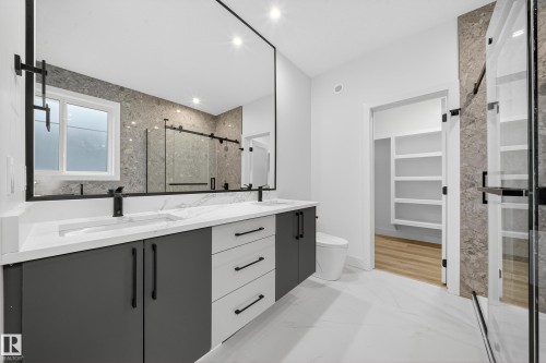 Modern bathroom featuring a double vanity with white countertops, dark gray cabinetry, and a large mirror - 6117 Crawford Drive, Edmonton, AB 