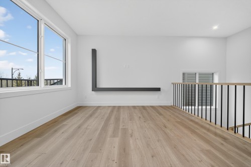 This versatile space features light-toned flooring, large windows providing natural light, and a modern wall-mounted shelf - 6117 Crawford Drive, Edmonton, AB 