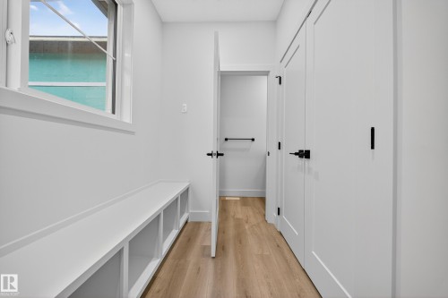 Hallway featuring light wood flooring, white walls, and a built-in bench with open storage compartments - 6117 Crawford Drive, Edmonton, AB 