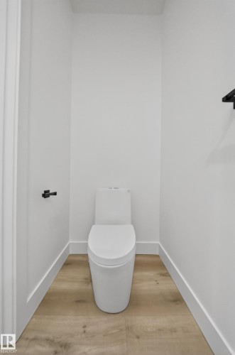 Modern powder room featuring a contemporary white toilet, light-toned flooring, and white baseboards - 6117 Crawford Drive, Edmonton, AB 