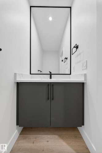 Contemporary vanity with a floating design, a sleek white countertop, and dark cabinetry with long black handles - 6117 Crawford Drive, Edmonton, AB 