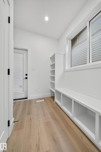 Entryway featuring light wood flooring, a window with horizontal blinds, built-in shelving, and a built-in bench with storage compartments - 6117 Crawford Drive, Edmonton, AB 