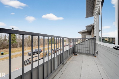 The property features an outdoor balcony with a metal railing, offering views of the surrounding area and a paved street - 6117 Crawford Drive, Edmonton, AB 