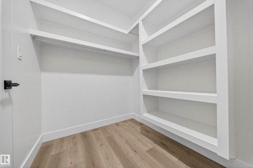 Well-appointed closet featuring light wood-style flooring, a hanging rod, and built-in shelving - 6117 Crawford Drive, Edmonton, AB 