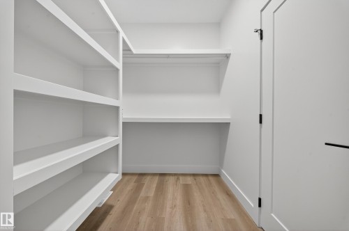 This space features extensive built-in shelving, a dedicated desk area, and wood-look flooring, complemented by a white door with black hardware - 6117 Crawford Drive, Edmonton, AB 