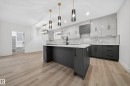 Modern kitchen featuring an island with a white countertop, dark grey cabinetry, and pendant lighting - 6117 Crawford Drive, Edmonton, AB 