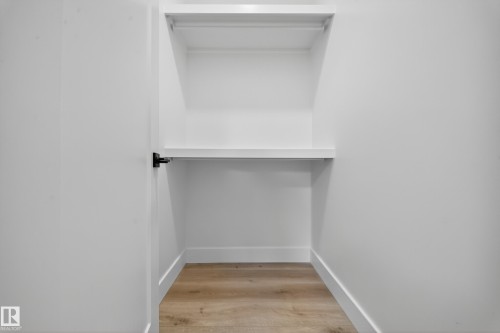 The property features a closet with white shelving and a hanging rod, complemented by light wood flooring - 6117 Crawford Drive, Edmonton, AB 