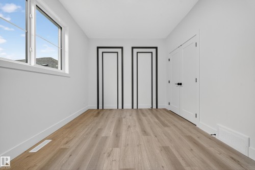 This room features light-colored plank flooring, white walls, and a large window - 6117 Crawford Drive, Edmonton, AB 