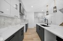 The kitchen features a contemporary design with white upper cabinetry and dark lower cabinetry, complemented by white countertops and a matching backsplash - 6117 Crawford Drive, Edmonton, AB 