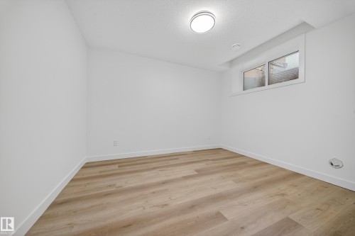 This room features light-colored plank flooring, white walls, and a ceiling-mounted light fixture - 6117 Crawford Drive, Edmonton, AB 