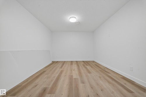 This versatile space features light-toned wood flooring, clean white walls, and a recessed ceiling light - 6117 Crawford Drive, Edmonton, AB 