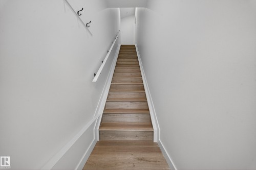 Staircase featuring light-toned wood treads and risers, a white handrail, and white walls - 6117 Crawford Drive, Edmonton, AB 