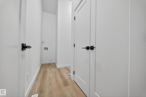 Laundry area with light wood-style flooring and white walls, featuring hookups for appliances - 6117 Crawford Drive, Edmonton, AB 