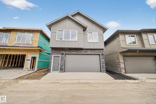 The property features a grey exterior with stone accents, a large garage, and a separate entrance - 6117 Crawford Drive, Edmonton, AB 