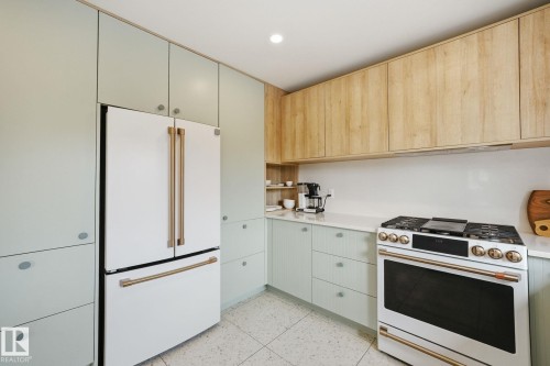 The kitchen features light-colored cabinetry, a white countertop, and a white refrigerator with gold-tone handles - 7235 112 Street, Edmonton, AB - Indoor Photo Showing Kitchen