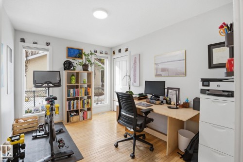 This versatile room features light-toned hardwood flooring, a ceiling-mounted light fixture, and large windows providing natural light - 7235 112 Street, Edmonton, AB - Indoor Photo Showing Office