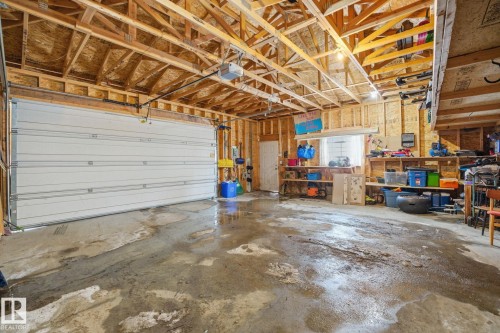 The property features a spacious garage with exposed wooden beams, a garage door, and ample storage shelving - 7235 112 Street, Edmonton, AB - Indoor Photo Showing Garage