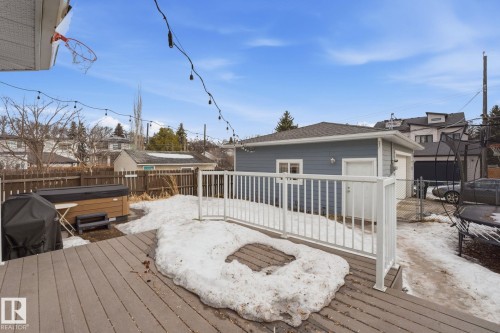 The property features an extensive deck area, a hot tub, and a detached garage with a light grey exterior - 7235 112 Street, Edmonton, AB - Outdoor With Deck Patio Veranda With Exterior