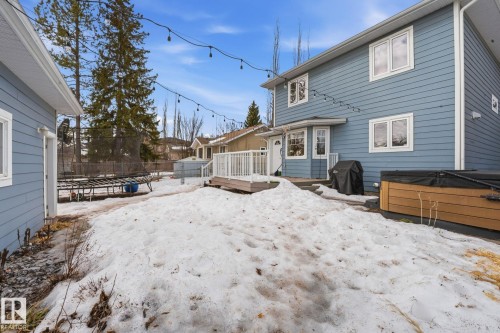 The property features a blue exterior, white-trimmed windows, and a raised wooden deck with white railings - 7235 112 Street, Edmonton, AB - Outdoor